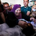 La abuela y los familiares de tres niños de la familia Al-Tanani, muertos en un ataque aéreo israelí, lloran sobre sus cuerpos, antes de su entierro en Beit Lahya, en el norte de la Franja de Gaza, el 14 de mayo de 2021.