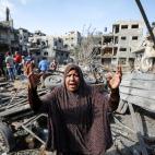 Una mujer palestina reacciona mientras ella y los palestinos registran sus pertenencias mientras los esfuerzos de rescate continúan para evacuar a los palestinos de los escombros de los edificios destruidos por los continuos ataques aéreos isr...