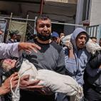 Los palestinos llevan el cuerpo envuelto del niño Ibrahim Alrantisi, muerto en un ataque aéreo israelí, antes de su entierro en Rafah, en el sur de la Franja de Gaza, el 14 de mayo de 2021.