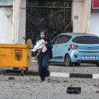 Una mujer palestina y su hija abandonan su vecindario para dirigirse a un lugar más seguro mientras los aviones de combate israelíes continúan los ataques aéreos