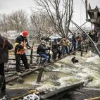 Un grupo de civiles ucranianos colabora en el env&iacute;o de armamento sobre un r&iacute;o tras el hundimiento de un puente
