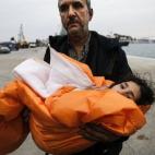 A su llegada al puerto de Mitilene en la isla griega de Lesbos, un refugiado sirio sostiene a su hija arropada con una manta, tras haber sido rescatados en pleno mar abierto.