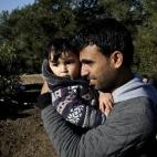 Un refugiado sirio abraza a su bebé mientras espera en un camino cercano a la costa en la ciudad de Dikili (Turquía), después de que los gendarmes turcos les impidieran zarpar hacia la isla de Lesbos.