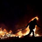 Un ciudadano arrastra una valla entre el fuego