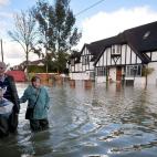 Dos residentes caminan a través del agua en Berkshire. La gran cantidad de agua caída en las zonas próximas a Londres ha forzado a los trenes que conectan la capital con Berkshire a reducir su velocidad.