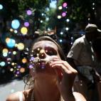 Una mujer sopla pompas al aire durante el desfile del bloco Cordão do Boitatá, con canciones tradicionales de samba y las populares marchinhas del carnaval brasileño por las calles empedradas del centro de Río, a una semana del carnaval.