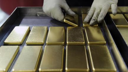 An employee arranges one kilogram gold bars at a mint refinery in Australia. Photographer: Carla Gottgens/Bloomberg