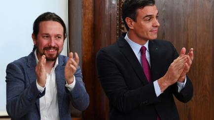 Leader of far left Podemos party, Pablo Iglesias (L) and Spanish caretaker prime minister and candidate for re-election, socialist Pedro Sanchez, applaud after signing their coalition government agreement at the Congress in Madrid on December 30...