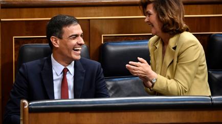 Candidate for re-election as prime minister for a second term, socialist Pedro Sanchez (L), laughs beside deputy prime minister Carmen Calvo after delivering his speech during the first day of the parliamentary investiture debate to vote through...