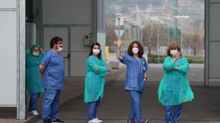 Health workers wave during a break outside the Burgos Hospital (UBU) on March 20, 2020, in Burgos, in northern Spain. - The coronavirus death toll rose to 1,002 in Spain after 235 people died in 24 hours, and the number of cases approached 20,00...