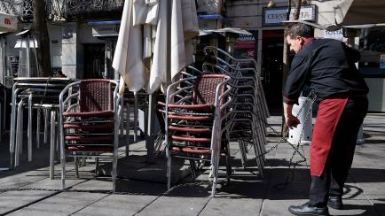 MADRID, SPAIN - MARCH 13: A waiter moves tables and chairs at Fuencarral street terraces after Madrid's Mayor announced that he would order the closure of terraces in the Spanish capital, and recommends the bars and restaurants to close due to t...
