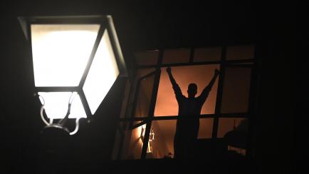 A person confined at home gestures and applauds from a window to pay tribute to the healthcare workers dealing with the COVID-19 disease in Madrid, on March 28, 2020, during a national lock-down to prevent the spread of the novel coronavirus pan...