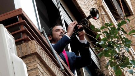 A man plays the trumpet from his window during home confinement due to the novel coronavirus on March 19, 2020 in Valencia. - Spain announced deaths due to the novel coronavirus had risen about 30 percent over the past 24 hours to 767. A total o...
