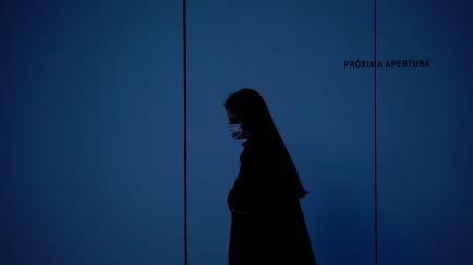 A woman wearing a face mask walks in Barcelona on March 21, 2020 during a national lockdown to prevent the spread of the new coronavirus. - Spain reported a 32 percent spike in new deaths from the coronavirus, bringing the country total to 1,326...