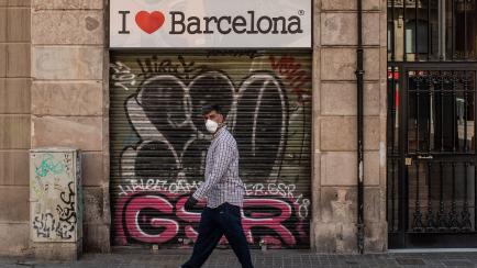 BARCELONA, SPAIN - MAY 06: A man wearing a protective face mask walk past a closed souvenir shop on May 06, 2020 in Barcelona, Spain. Despite of small businesses are allowed to open since last Monday, many shops and restaurants remain closed. Sp...