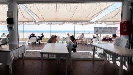 People enjoy the sunny weather at a terrace in La Malvarrosa beach in Valencia, on May 19, 2020, as some Spanish provinces are allowed to ease lockdown restrictions amid the coronavirus (COVID-19) outbreak. - Spain began last week a three-phase ...