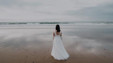 Rear view of a young woman in a beautiful wedding dress in the beach