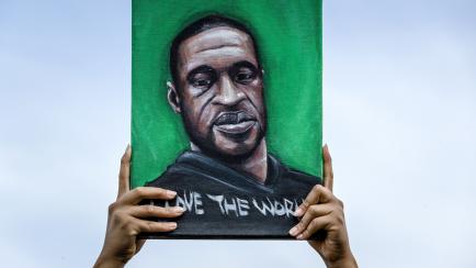 A protester holds a banner depicting George Floyd during a demonstration against racism and police brutality in the US on the Glitterplein near the Erasmus Bridge in Rotterdam on June 3, 2020. (Photo by Remko DE WAAL / ANP / AFP) / Netherlands O...