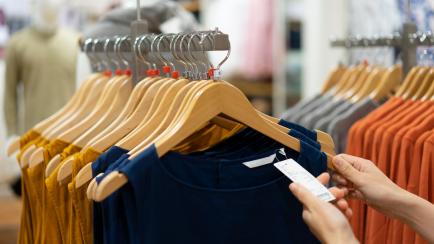 Una persona, mirando la etiqueta de una prenda de ropa en una tienda.