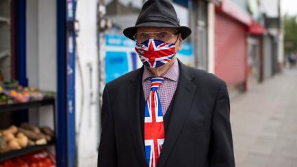 LONDON, UNITED KINGDOM - JUNE 12: A an walks down a high street in East London wearing a matching Union Jack tie and face mask on June 12, 2020 in London, England.  As the British government further relaxes Covid-19 lockdown measures in England,...