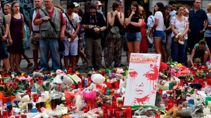Un grupo de personas coloca flores y velas en uno de los homenajes populares de las víctimas del atentado en Las Ramblas, tres días después del atentado. 