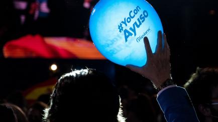 Un simpatizante del PP sostiene un globo con el lema 'Yo con Ayuso' en la fiesta de Génova de este martes.