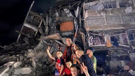 Un grupo de palestinos hacen gestos de victoria ante un edificio destrozado por las balas, anoche, en Gaza capital. 