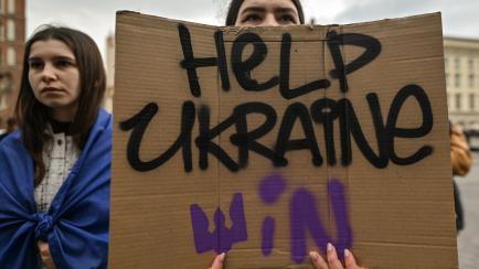 Una manifestante porta un cartel pidiendo ayuda para que Ucrania gane, en una protesta en Varsovia, Polonia. 