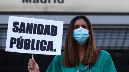 Una médica del hospital universitario Gregorio Marañón sujeta una pancarta que dice 'Sanidad pública' durante una propuesta por las condiciones laborales.