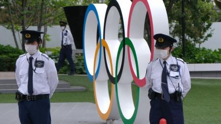 Dos vigilantes protegen una escultura de los aros olímpicos por una protesta ciudadana en Tokio