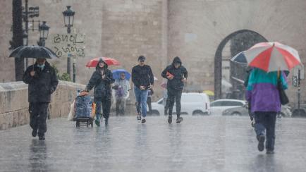 Varias personas, bajo una lluvia fuerte en Valencia.