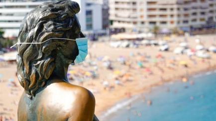 Detalle de la estatua de Ava Gadner con la que la localidad gironina de Tossa de Mar recuerda el rodaje de la pelicula 'Pandora' y que ahora luce una mascarilla. 