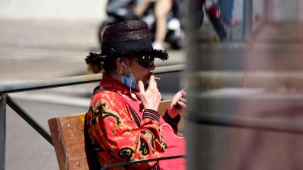 MADRID, SPAIN - JUNE 03: A woman wearing a protective face mask smokes a cigarette on June 03, 2020 in Madrid, Spain. WHO urges national authorities to follow its recommendations and their commitments under the WHO Framework Convention on Tobacc...