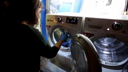 Una mujer poniendo la lavadora.