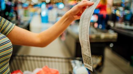 Una mujer revisa el ticket de la compra en un supermercado.