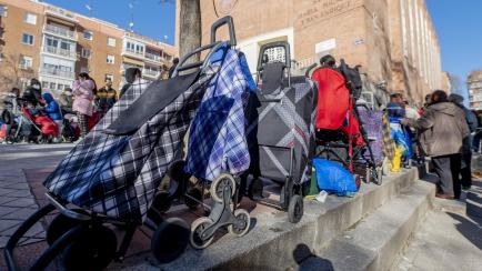Varias personas hacen cola para recibir alimentos de la Fundación Madrina, en la plaza de San Amaro, en Madrid.