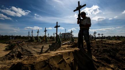 Un voluntario coloca una cruz en un cementerio con cuerpos sin identificar en Bucha.