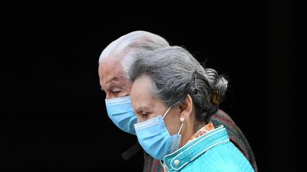 An elderly couple wearing face masks walks in Madrid on April 30, 2020 during a national lockdown to prevent the spread of the COVID-19 disease. - Spain counted another 268 people who have died from the coronavirus, the lowest daily number since...