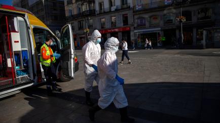Health workers in personal protection equipments walk at the Puerta del Sol in Madrid, Spain, Friday, Aug. 28, 2020. Spanish authorities have announced new restrictions to prevent COVID-19. (AP Photo/Andrea Comas)