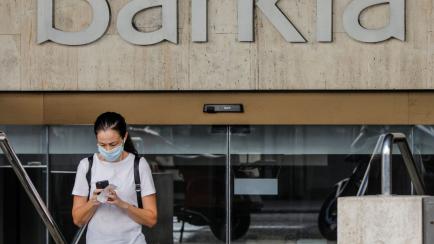 VALENCIA, SPAIN - SEPTEMBER 04: A woman walks close to Bankia SA headquarters building in Valencia, Spain, on September 04, 2020. The spanish banks CaixaBank and Bankia are studying a merger process in order to increase their profitability in th...
