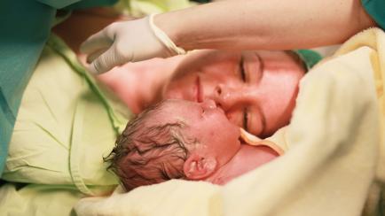 Una mujer mira a su bebé tras el parto.