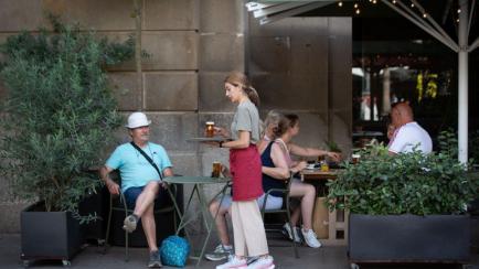 Una camarera atiende a un cliente en Barcelona durante el mes de junio.