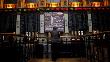 A trader looks at an electronic board showing the Ibex35 during trading at the Madrid bourse April 19, 2012. France and Spain sold all the bonds they wanted at auction on Thursday, though for Spain the cost was rising yields, indicating growing ...