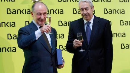 Rodrigo Rato (L), chairman of Spanish savings bank Bankia, toasts with Spanish Stock Exchange president Antonio Zoido during its bourse debut in Madrid July 20, 2011. Shares in Bankia made a tepid bourse debut on Wednesday, opening below a deepl...