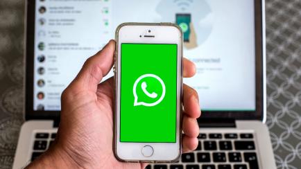 Un móvil iniciando WhatsApp, con un portátil con WhatsApp Web de fondo.