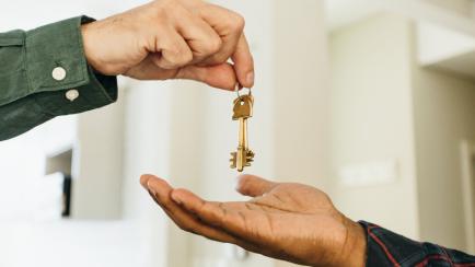 Relator giving house keys to new owner hands close-up