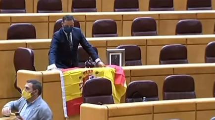 Un senador del PP recibe a Iglesias con la bandera de España y una foto del rey.