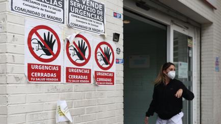 Una sanitaria en el PAC Ángela Uriarte de Madrid, junto con unos carteles que rezan 'Urgencias Cerradas, tu salud vendida', el 21 de octubre de 2022 en Madrid.
