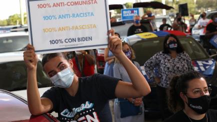 MIRAMAR, FLORIDA - OCTOBER 13: Wearing a face masks to reduce the risk posed by the coronavirus, Sophia Hildalgo (L) and Amore Rodriguez of Miami stay with their car decorated in Cubans for Biden paint as Democratic presidential nominee Joe Bide...