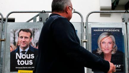 Un hombre pasa frente a dos murales del presidente francés Emmanuel Macrón, de centro, y la candidata Marine Le Pen, de extrema derecha, en Anglet, al suroeste de Francia.